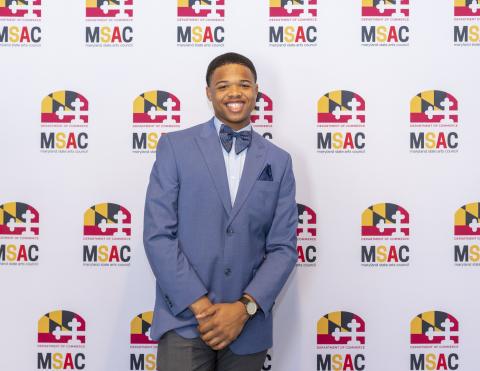 2020 Maryland State POL Champion Randolph Smith stands in front of a step and repeat banner with the MSAC Logo.