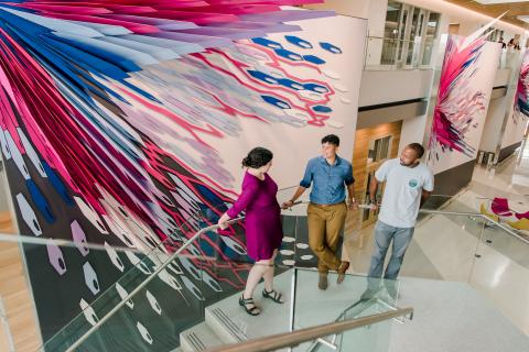 People on the stairs standing in front of a mural