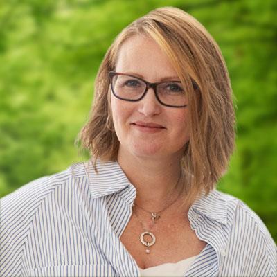 Tammy Oppel headshot. Women smiling with glasses and a light blue collared shirt.