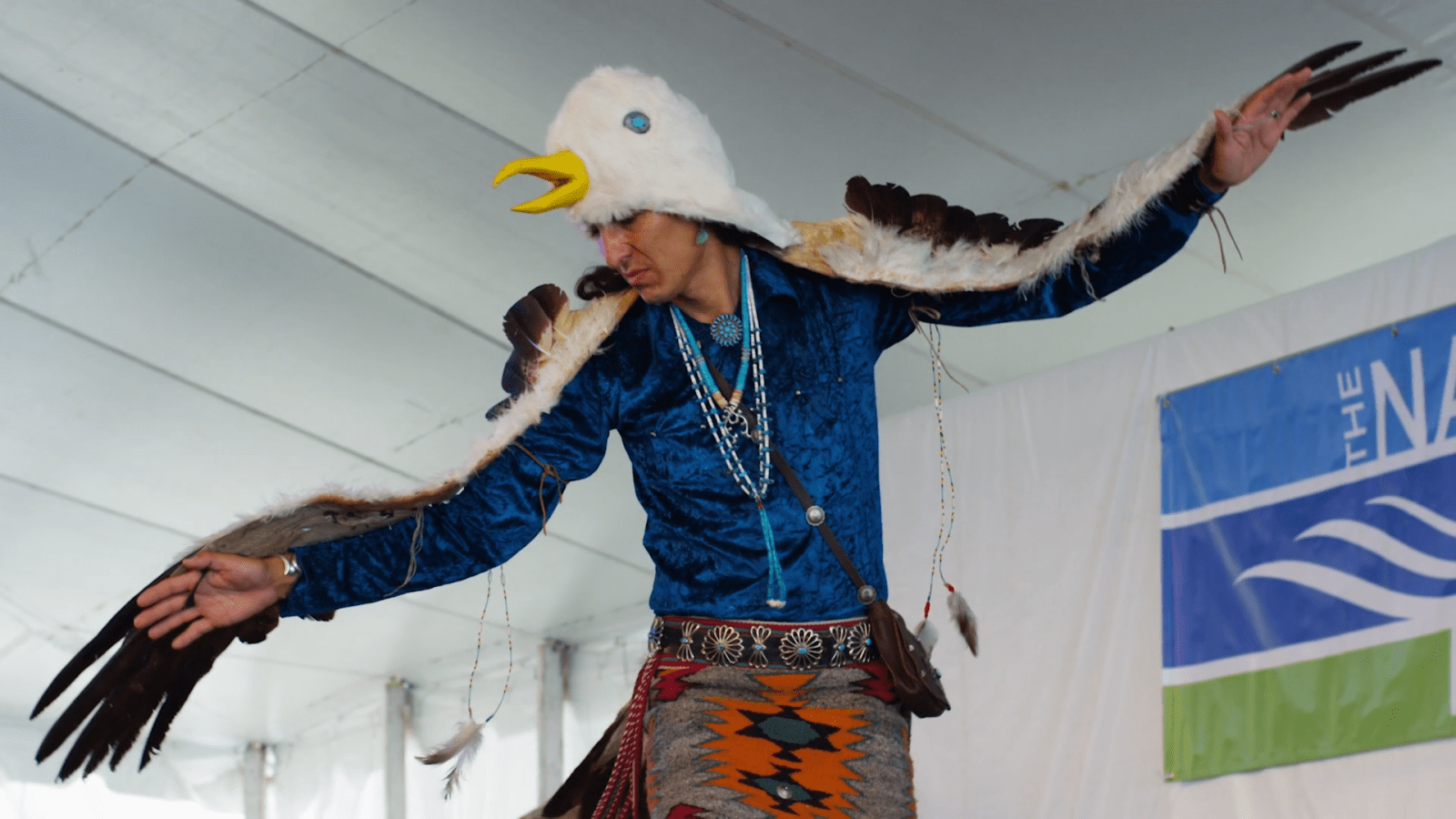 Man in a Native eagle dress performs on stage