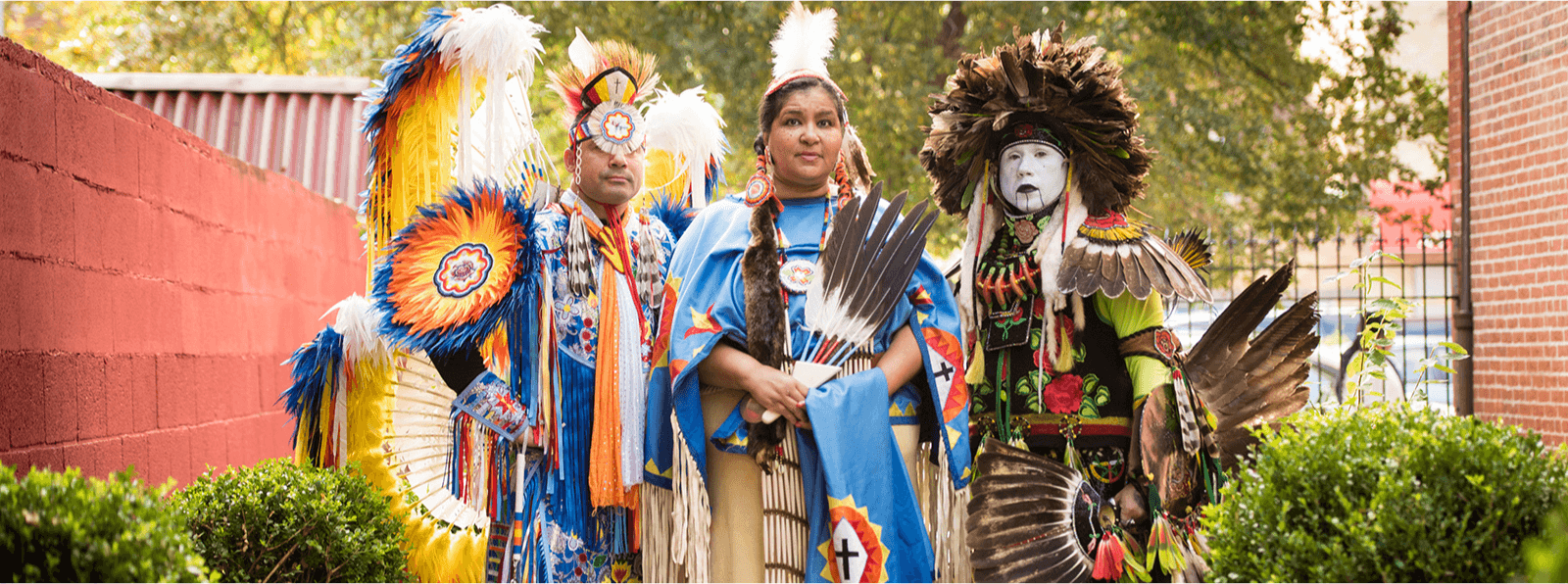 Three people in Lumbee, Tusarora, and Powhatan dress face the camera