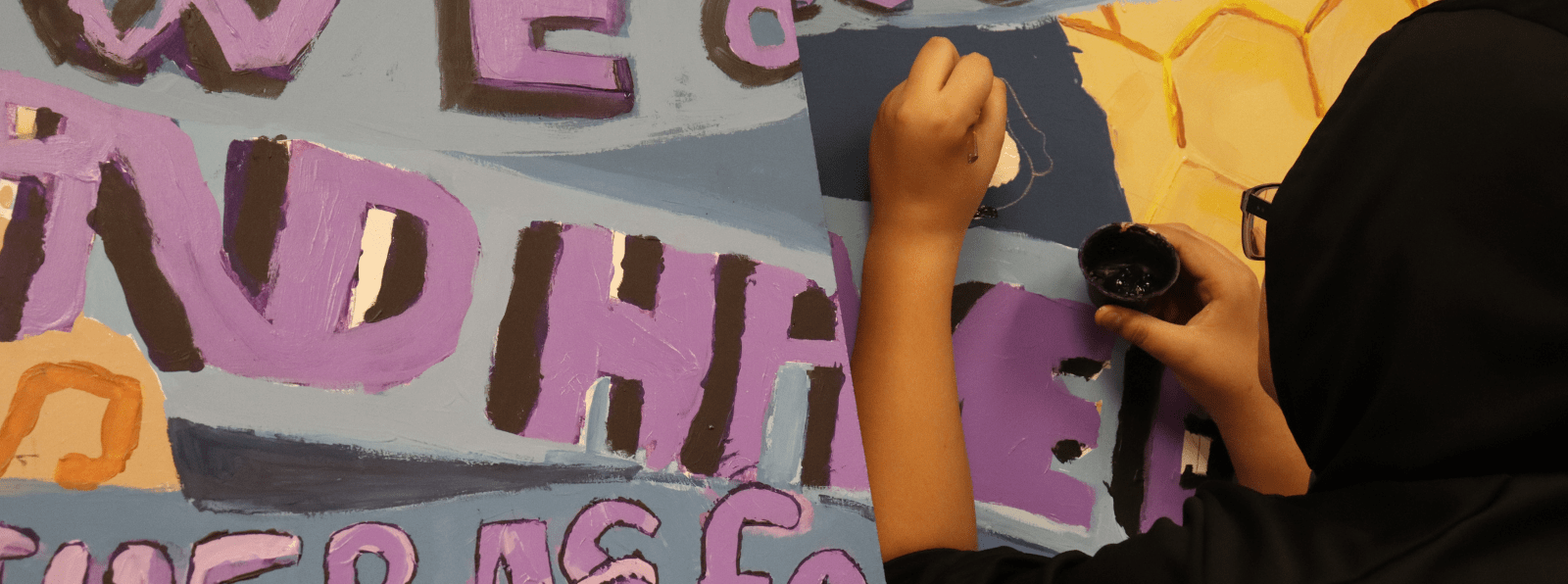 A person is painting a mural that includes text.
